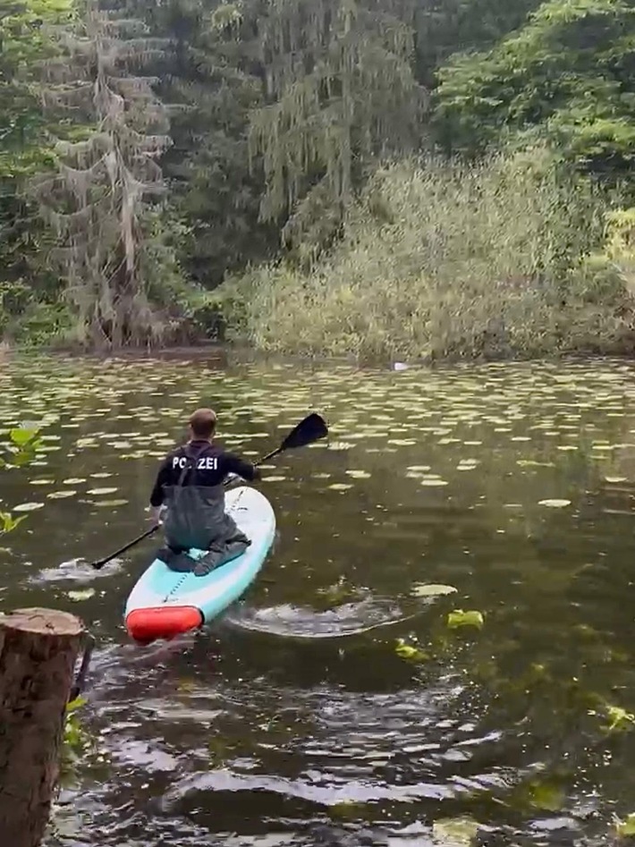 Ein Polizeibeamter aus Alfeld nutzt sein Stand-Up-Paddle-Board, um einen treibenden Müllsack aus dem Klugen Teich zu bergen.
